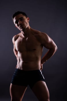 Muscular shirtless young man standing confident, front view, looking at a camera