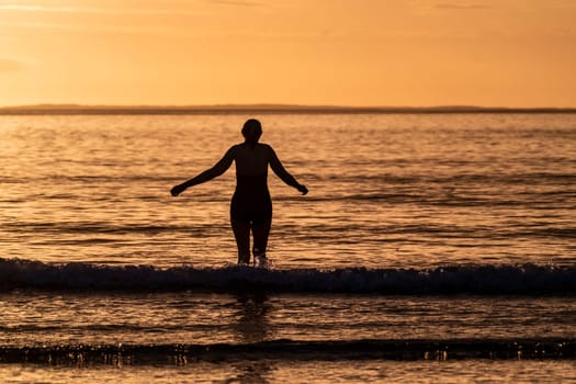 Silhouette of female swimmer going into the Atlantic ocean in Ireland.