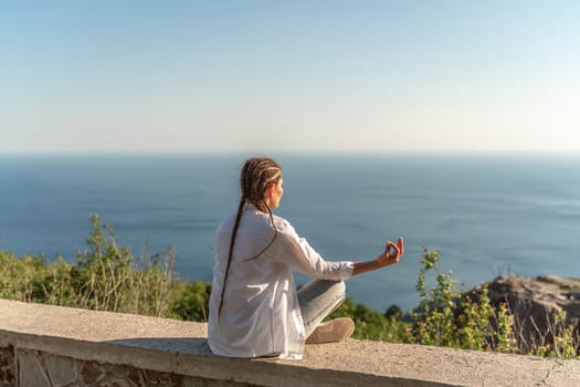 Profile of a woman doing yoga in the top of a cliff in the mountain. Woman meditates in yoga asana Padmasana.