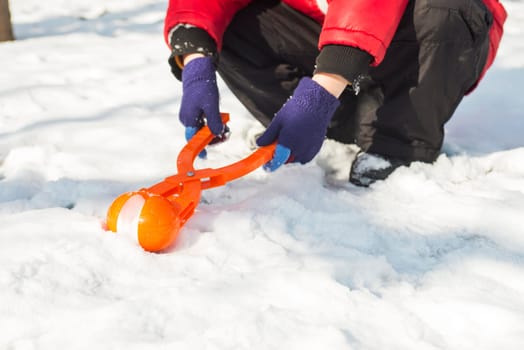 A device for sculpting snowballs in childrens hands against a background of snow. Childrens winter games of snowballs.