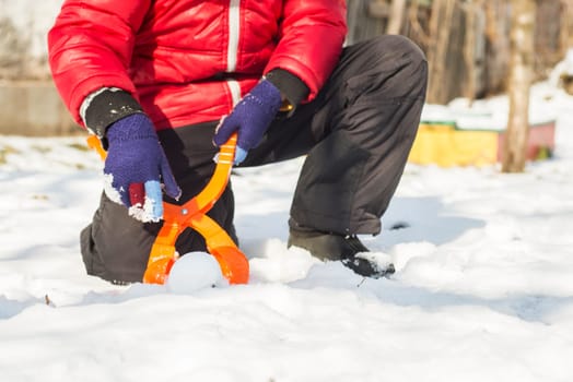 A device for sculpting snowballs in childrens hands against a background of snow. Childrens winter games of snowballs.