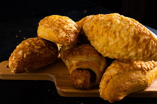 Freshly backed french croissant shiny in the rays of morning sun, dark background, kitchen