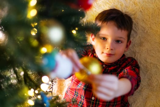 Little cute child decorating the Christmas tree on Christmas Eve at home.