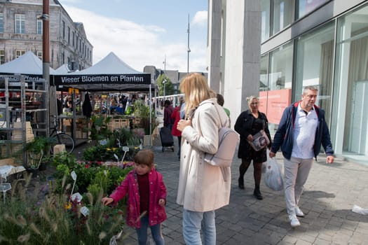 People walk among Variety of flower choices at the market in the central square in Maastricht, Netherlands, August 27, 2021. High quality photo
