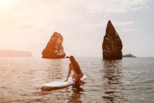 Close up shot of beautiful young caucasian woman with black hair and freckles looking at camera and smiling. Cute woman portrait in a pink bikini posing on a volcanic rock high above the sea