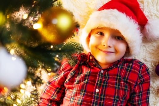 Little cute child decorating the Christmas tree on Christmas Eve at home.