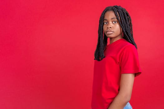 African woman standing and looking at camera in studio with red background