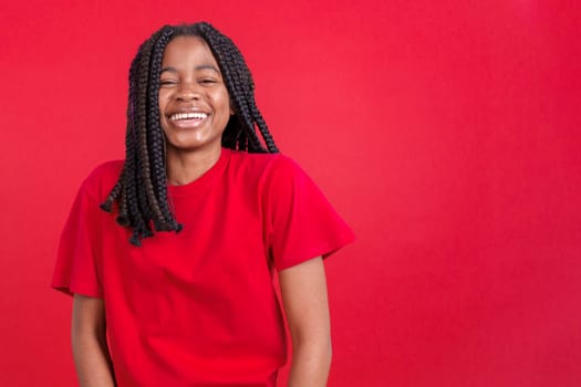 Happy african woman smiling at the camera in studio with red background