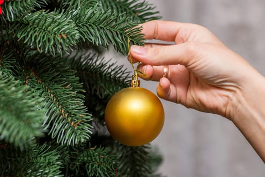 Girl decorates a Christmas tree. Close up image of womans hand decorating Christmas tree with bubblers.