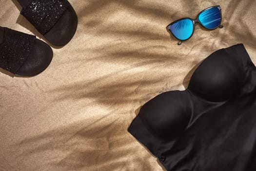Top view of summer accessories on sandy beach. Shadow from a palm leaf. Still life. Copy space. Flat lay