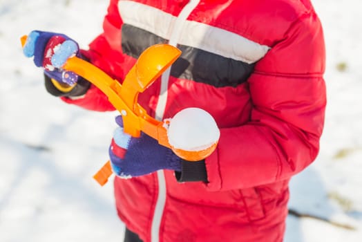 A device for sculpting snowballs in childrens hands against a background of snow. Childrens winter games of snowballs.