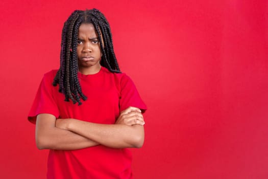 African woman crossing the arms with an angry expression in studio with red background