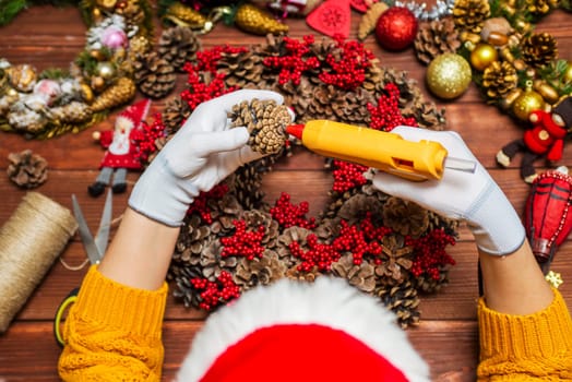 Female hands white gloves with a glue gun make Christmas decorations or toys. Making New Year decoration. Christmas ornaments.