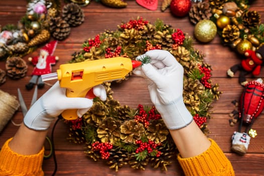 Creating a Christmas wreath with womens hands on a wooden background. Concept of preparation for Christmas and New Year. Decoration for the house for Christmas.