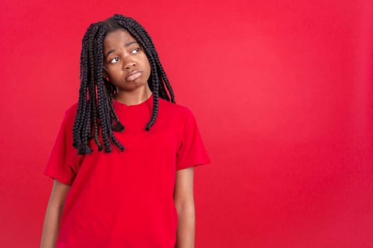 African woman with sad expression looking away in studio with red background