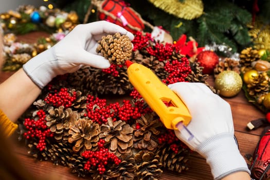 Creating a Christmas wreath with womens hands on a wooden background. Concept of preparation for Christmas and New Year. Decoration for the house for Christmas.