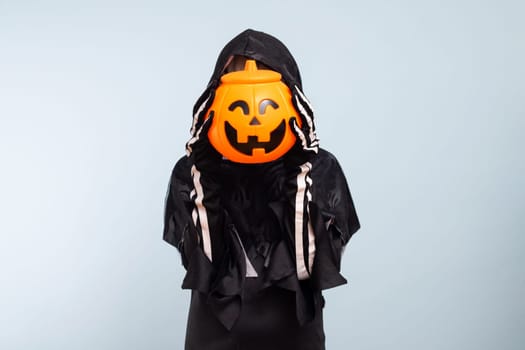 Happy Halloween. Cute little boy in a costume with a pumpkin basket jack-o-lantern.