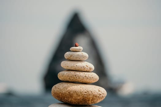 Pyramid stones on the seashore with warm sunset on the sea background. Happy holidays. Pebble beach, calm sea, travel destination. Concept of happy vacation on the sea, meditation, spa, calmness.