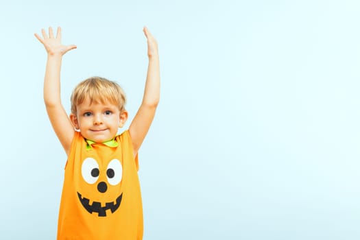 Happy Halloween. Cute little boy in pumpkin costume on a blue background.