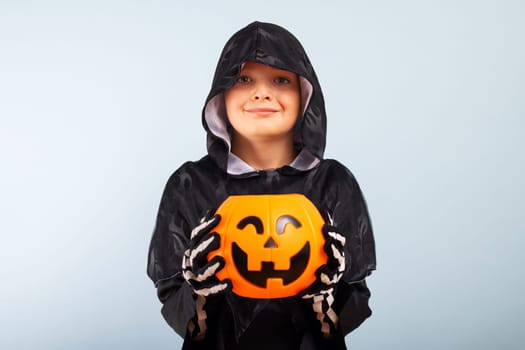 Happy Halloween. Cute little boy in a costume with a pumpkin basket jack-o-lantern.