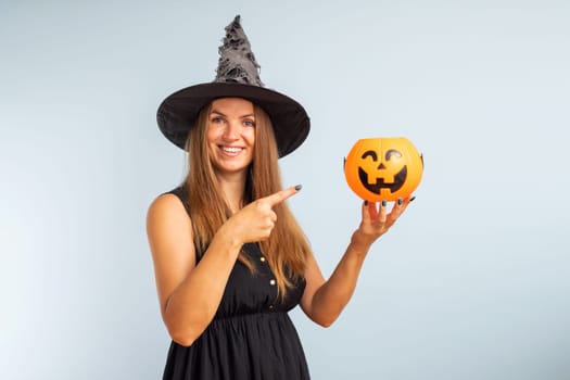 Happy Halloween. Happy young woman in halloween witch costume with pumpkin basket jack-o-lantern.