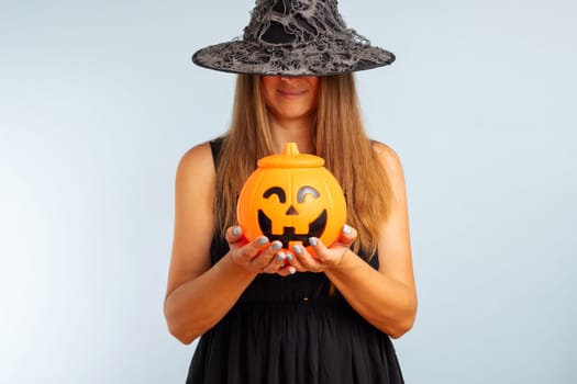 Happy Halloween. Happy young woman in halloween witch costume with pumpkin basket jack-o-lantern.