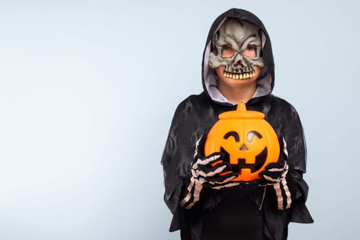 Happy Halloween. Cute little boy in a costume with a pumpkin basket jack-o-lantern.