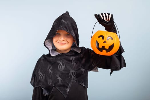 Happy Halloween. Cute little boy in a costume with a pumpkin basket jack-o-lantern.