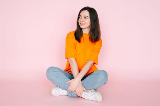 Dreaming in Serenity: Beautiful Woman Seated Comfortably in Lotus Position, Gazing into Empty Space, Yearning for a New Love - Tranquil Mood on Pink Background.