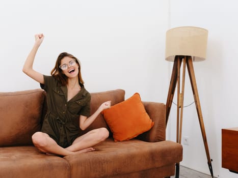 Woman model sitting on the couch at home smile, surprise, joy and relaxation, modern interior lifestyle, copy space, fall color palette. High quality photo