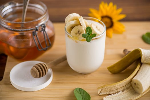 Sweet homemade yogurt with bananas and honey in a glass