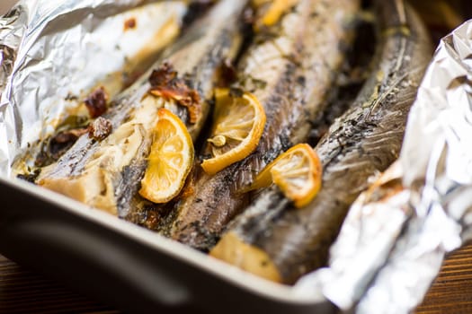 Baked fish with seasonings and spices in foil, in a ceramic form.