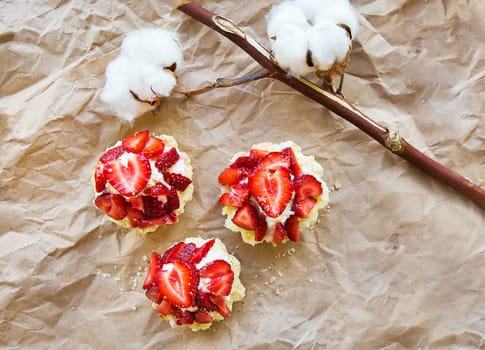 Beautiful muffin with fresh strawberries lies on craft paper, close-up.