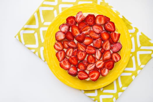 Beautiful and delicious strawberry cake stands on a yellow napkin.