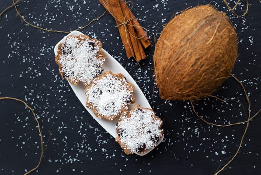 coconut muffins with chocolate on a black background and whole coconut
