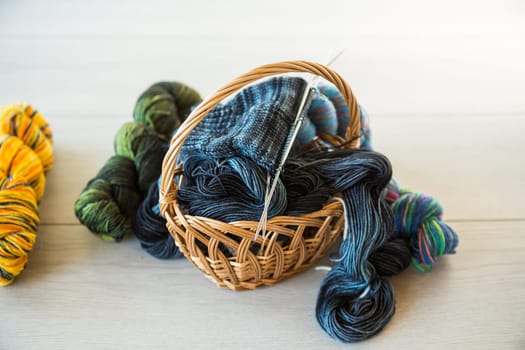 Colored threads, knitting needles and other items for hand knitting, on a dark wooden table .