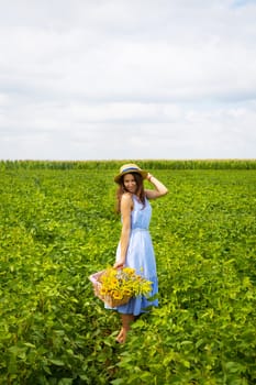 beautiful girl in a hat and blue board is standing on a green field.
