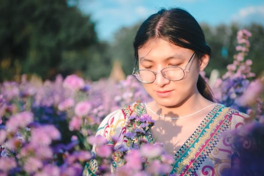 Beautiful asian woman (LGBTQ) natural makeup wear fashion relax clothes posing at nature of flower park or flower garden field lush growing for travel popular landmark in asia outdoor fashion style