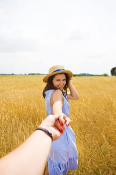 a girl in a blue dress is standing with her back in a wheat field.
