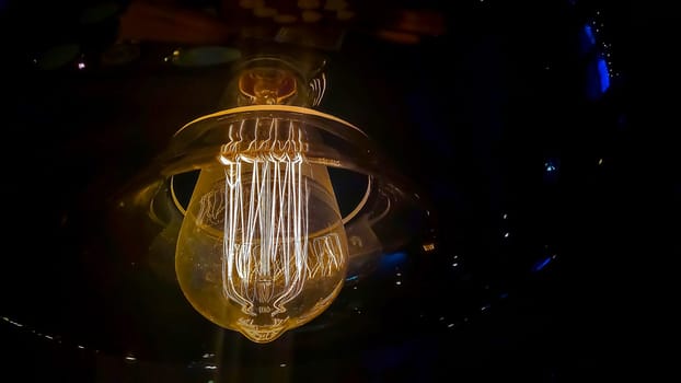 Vintage lightbulb on dark background with bright yellow shining wire