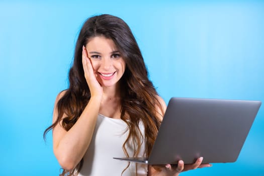Young woman holding notebook advertises modern media service at blue studio wall