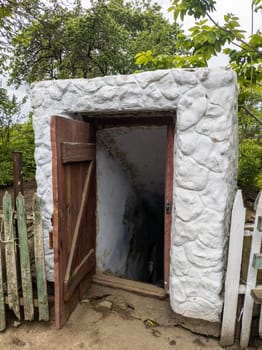 Open door historic vintage root cellar dug underground in the countryside near the trees