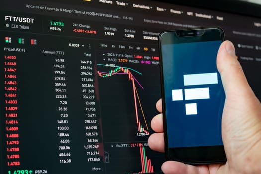 Man holding phone with FTX logo. Global fall of cryptocurrency graph - FTT token fell down on the chart crypto exchanges on app screen. FTX exchange bankruptcy and the collapse depreciation of token