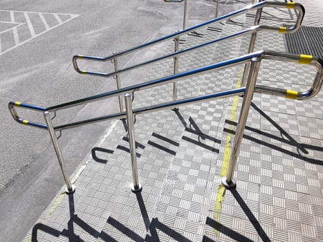 Handicapped symbol at parking space with Slope walkway for disabled people, people pushing strollers, carts with stainless bars to prevent falling.