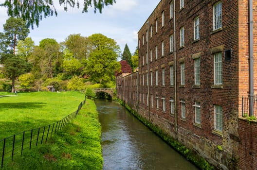 Exterior of restored cotton spinning and weaving mill in north of England with river