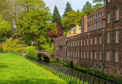 Exterior of restored cotton spinning and weaving mill in north of England with river