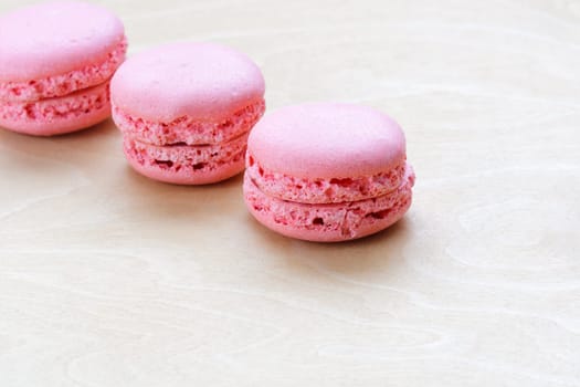 pink macaron on a light wooden background