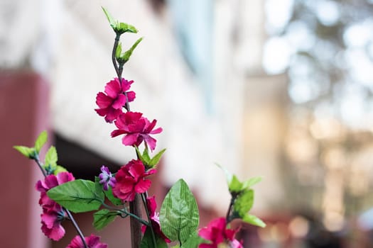 Branch with artificial violet plastic flowers close up, copy space