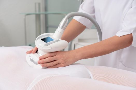 Woman in special white suit getting anti cellulite massage in a spa salon. LPG, and body contouring treatment in clinic