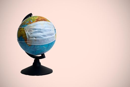 Globe in a medical protective mask on a red background, copy space